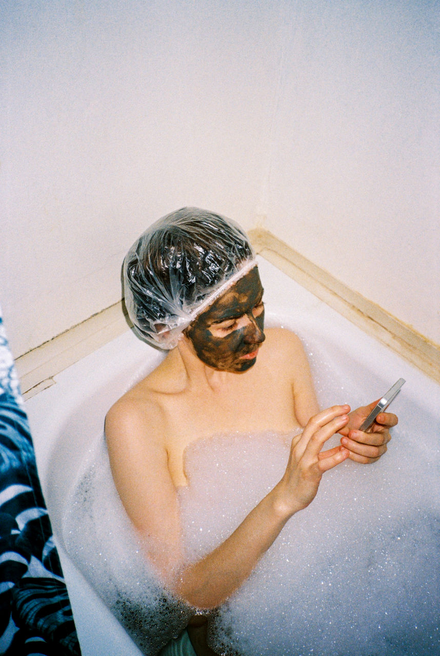 Frau in der Badewanne mit Smartphone