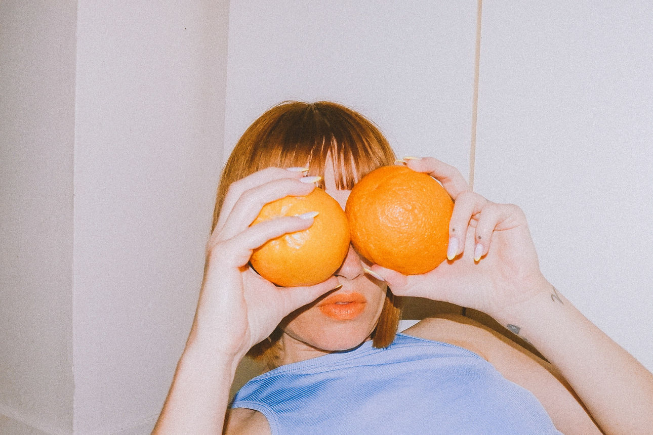 Frau hält sich Orangen vor die Augen