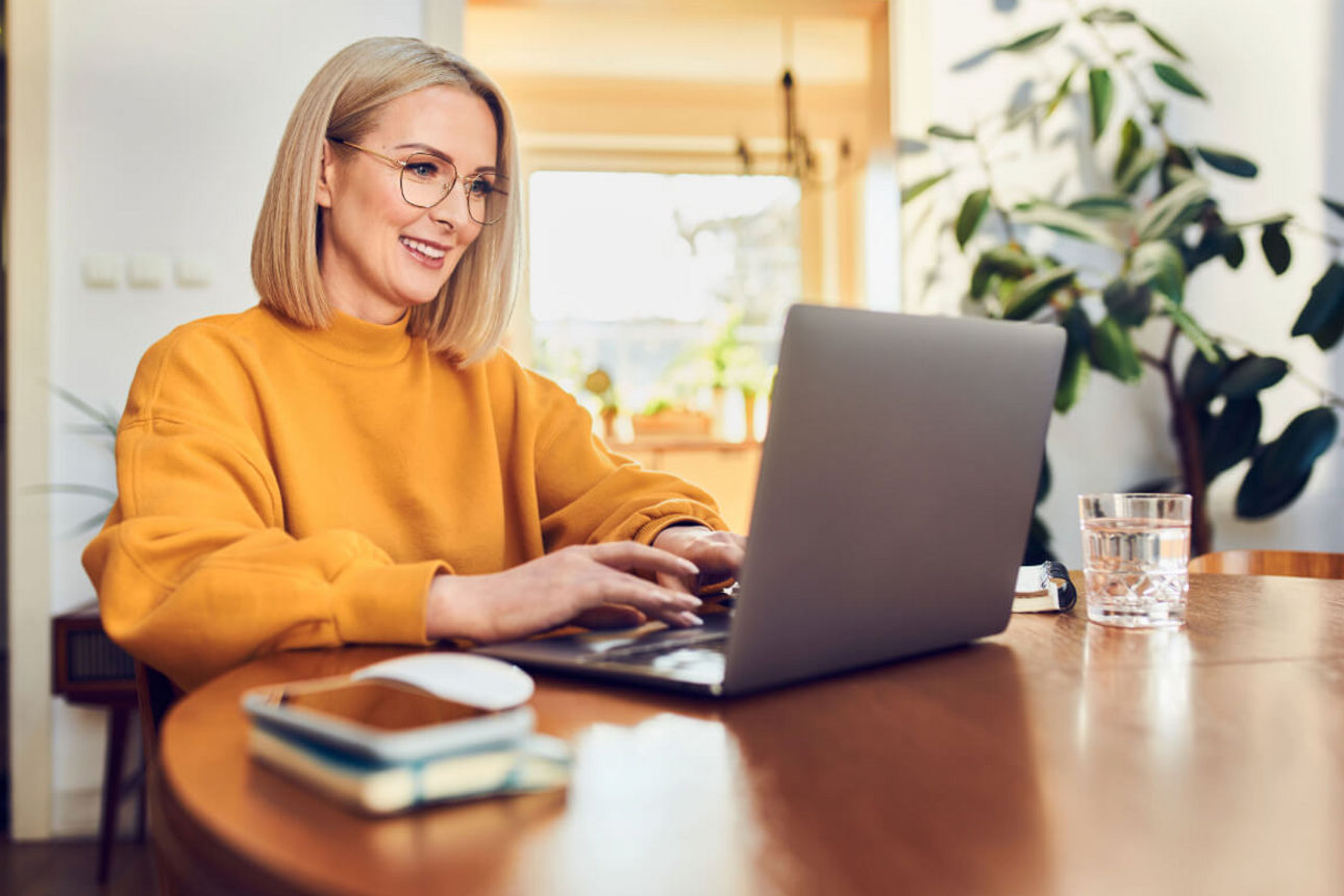 Eine Frau sitzt am Notebook und meldet sich für den Newsletter an. 