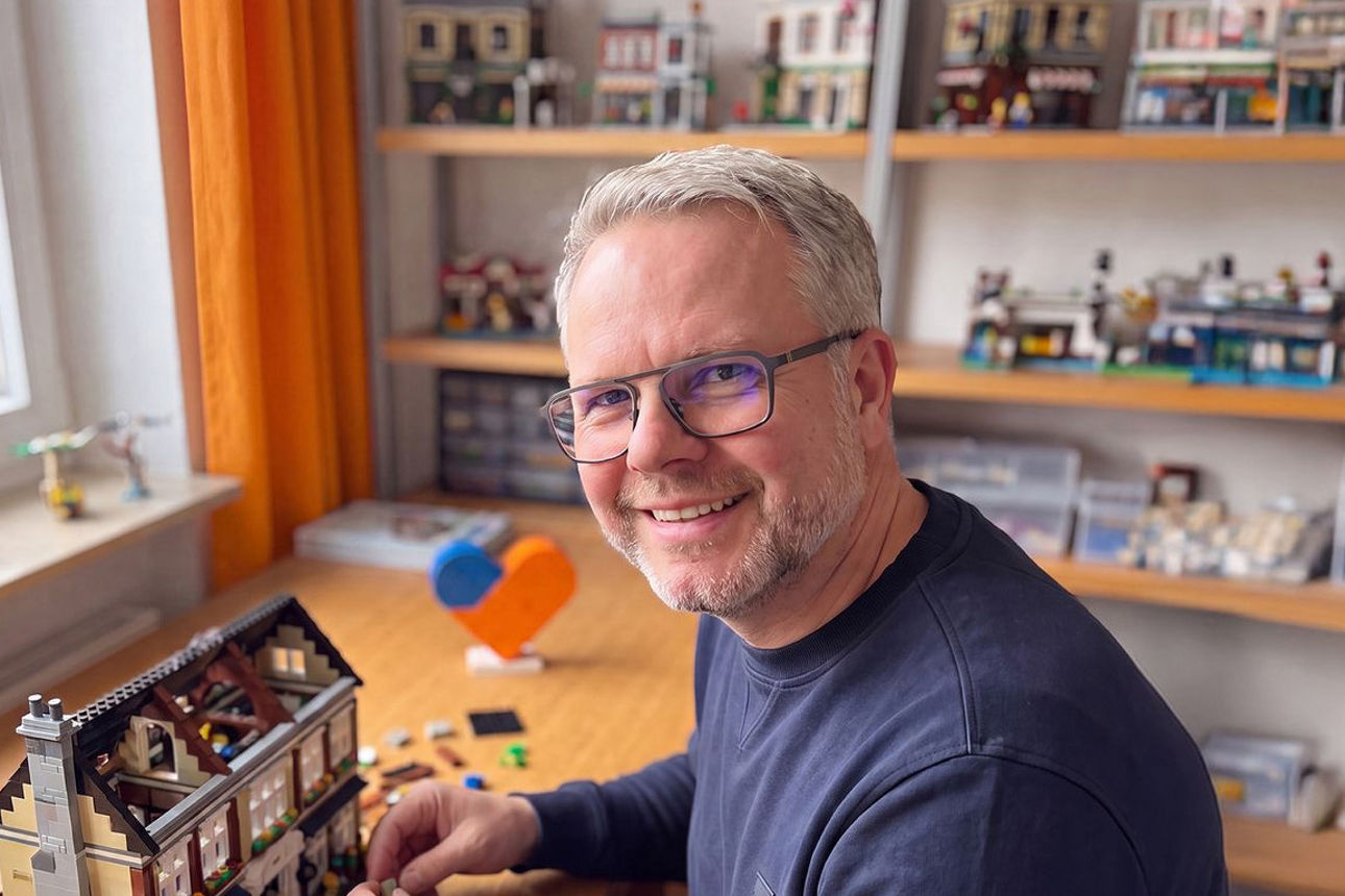 Ein Mann sitzt an einem Tisch und baut mit Lego
