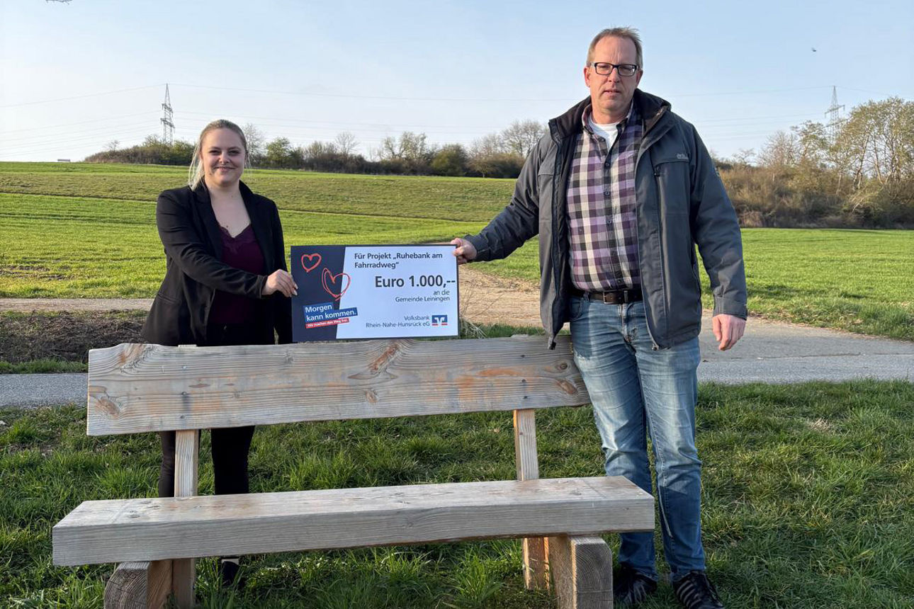 Zwei Erwachsene halten einen Spendenscheck in der Hand. 