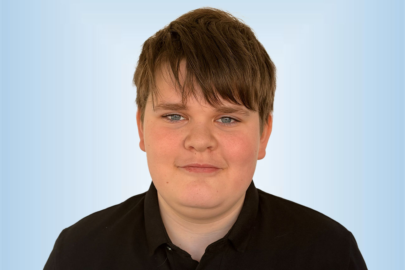 Praktikant Leo Lehrer vor einem blauen Hintergrund 