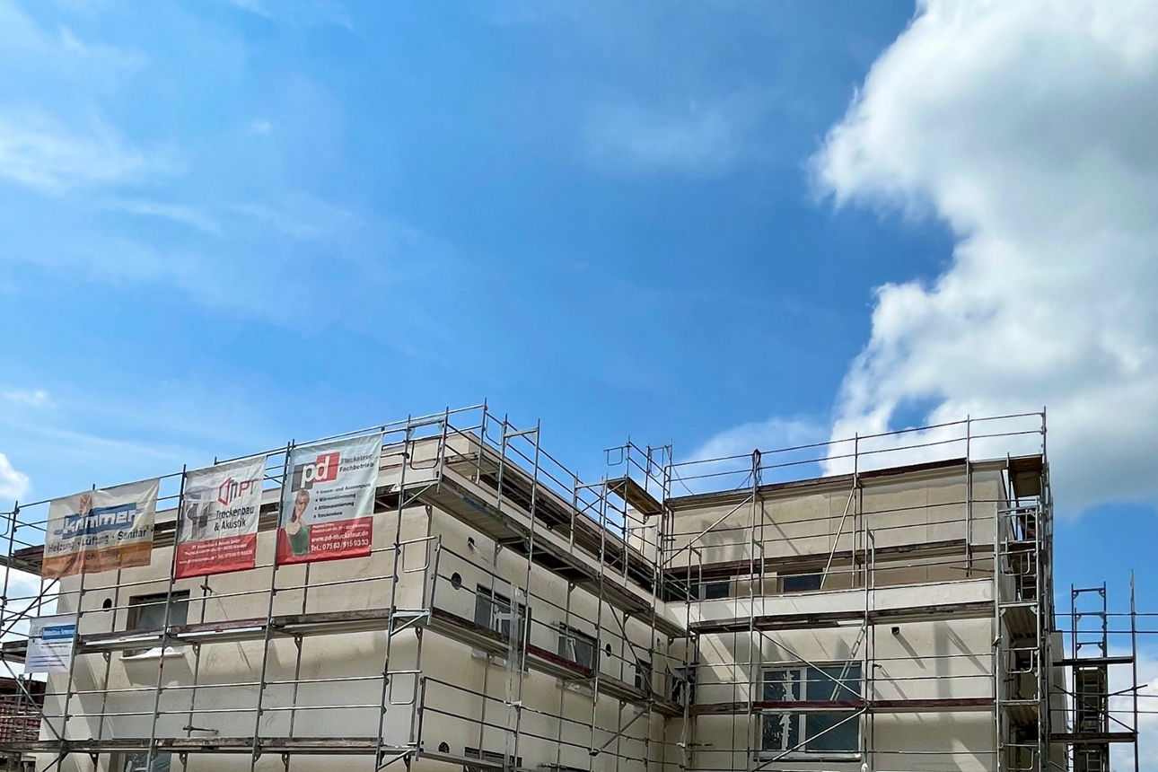 Einfahrt in eine Tiefgarage, dahinter ein Rohbau mit Baugerüsten.