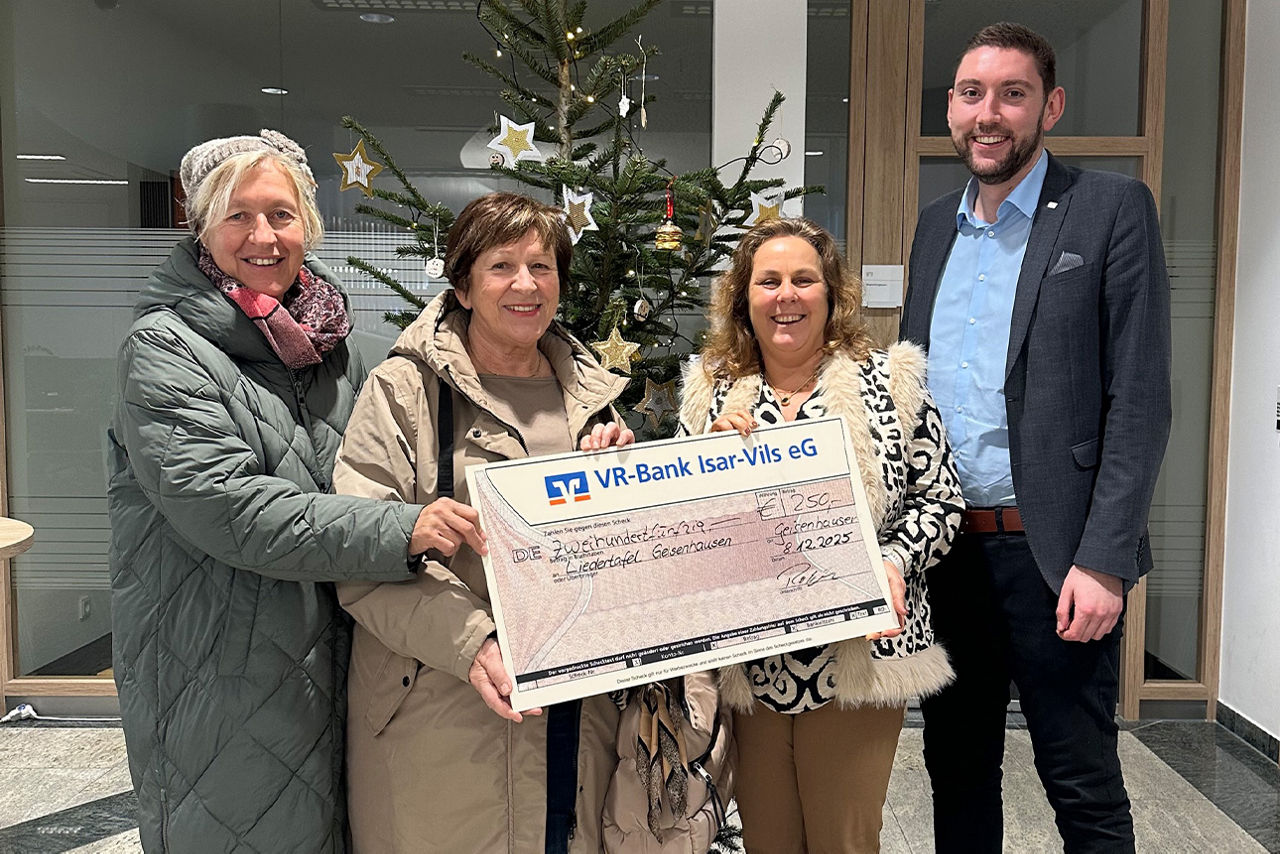 Drei Frauen und ein Mann lächeln in die Kamera. Sie halten einen Riesenspendenscheck in der Hand.