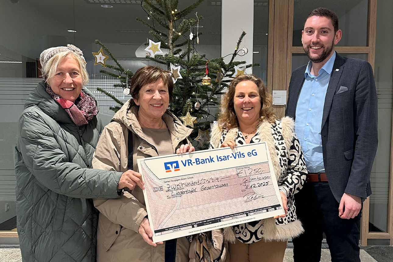 Drei Frauen und ein Mann lächeln in die Kamera. Sie halten einen Riesenspendenscheck in der Hand.