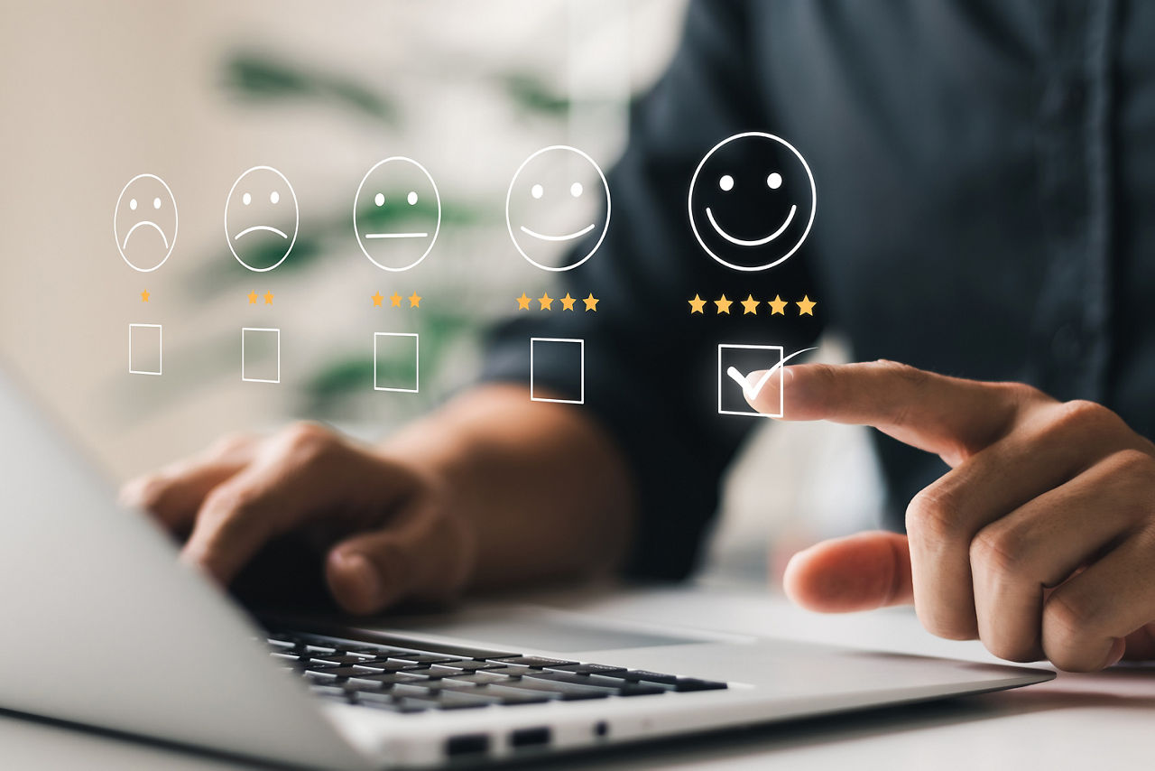 Unterschiedliche Smileys von traurig bis fröhlich von 1-5 Sternen vor einem Laptop