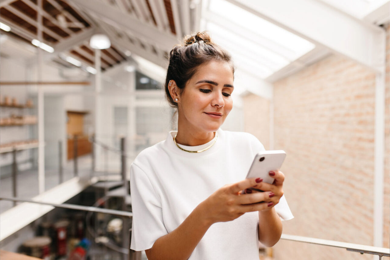 Eine Frau mit Smartphone in der Hand übermittelt positives Feedback an ihre Bank.