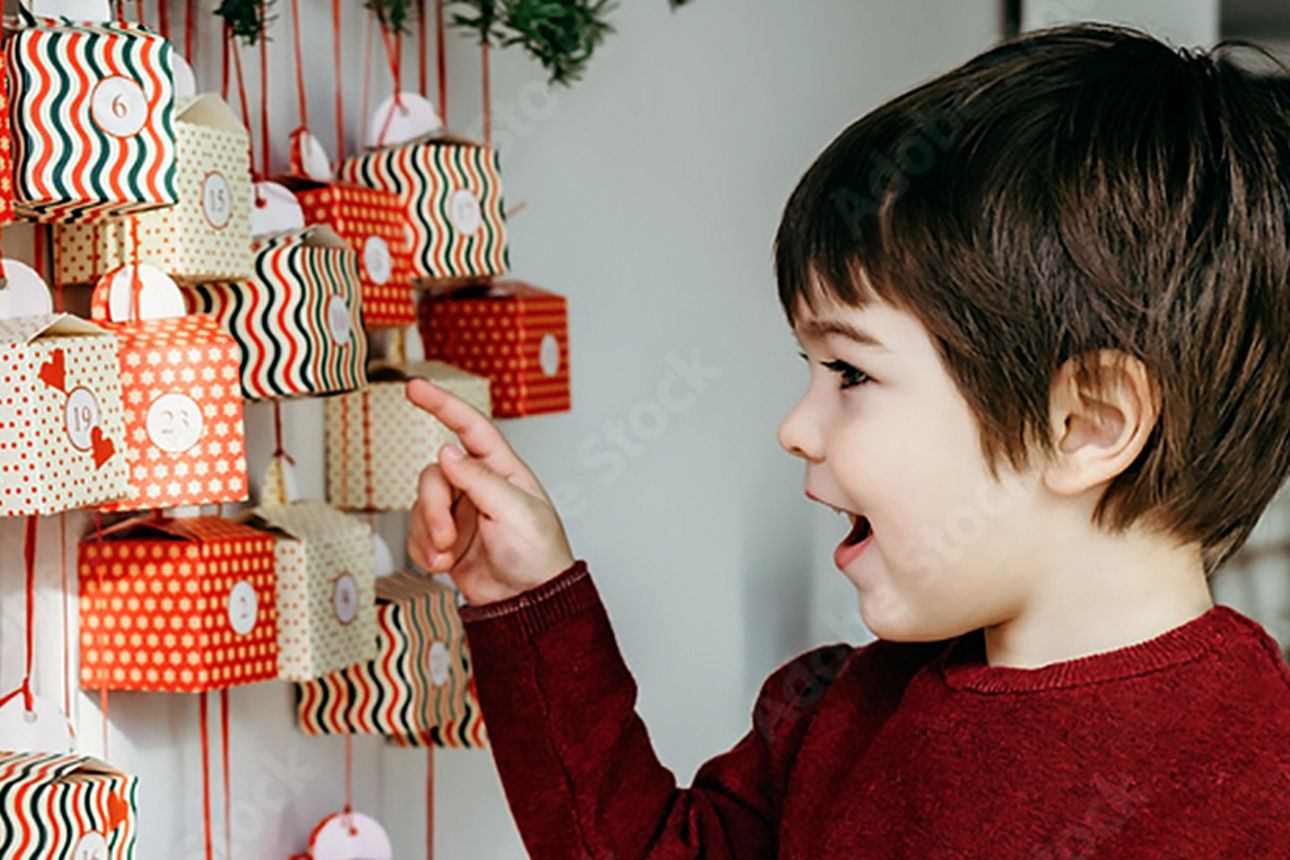Ein Junge zeigt lächelnd auf einen Adventskalender