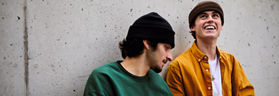 Zwei junge Männer sitzen an einer Wand