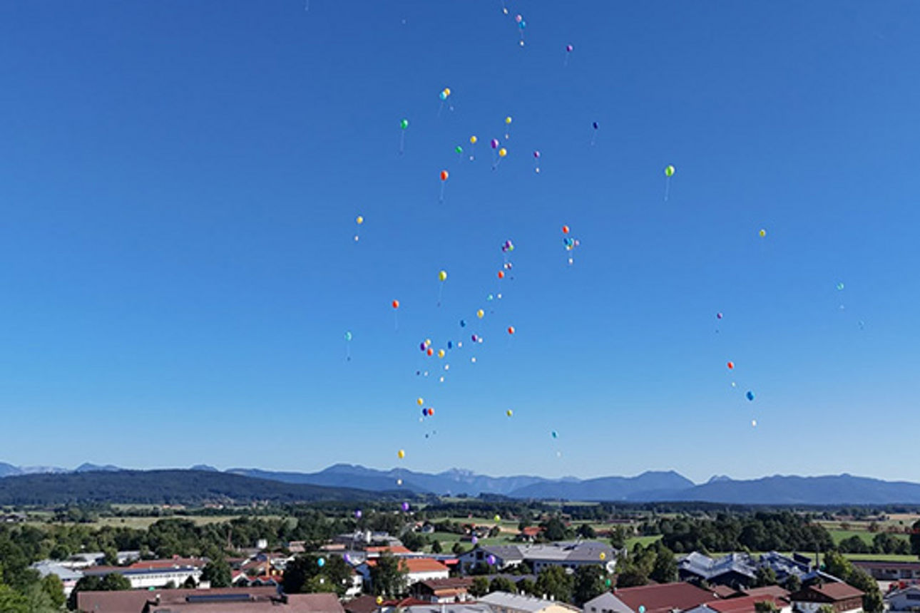 Luftballone fliegen. Im Hintergrund die Alpen.