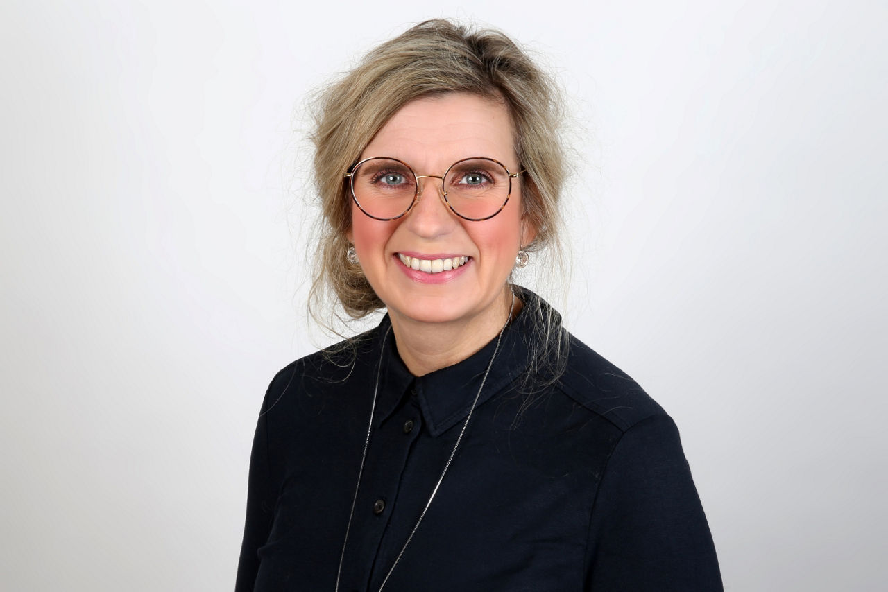 Eine lächelnder Frau schaut in die Kamera.