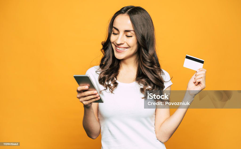 A girl with a credit card in one hand and a mobile phone in other is showing her pleasant