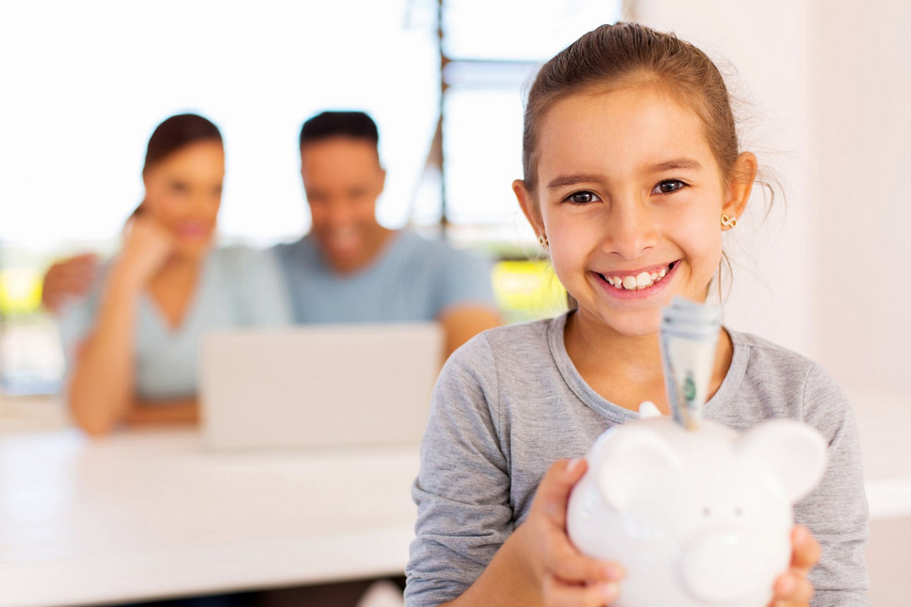  Ein Mädchen hält ihr Sparschwein in der Hand