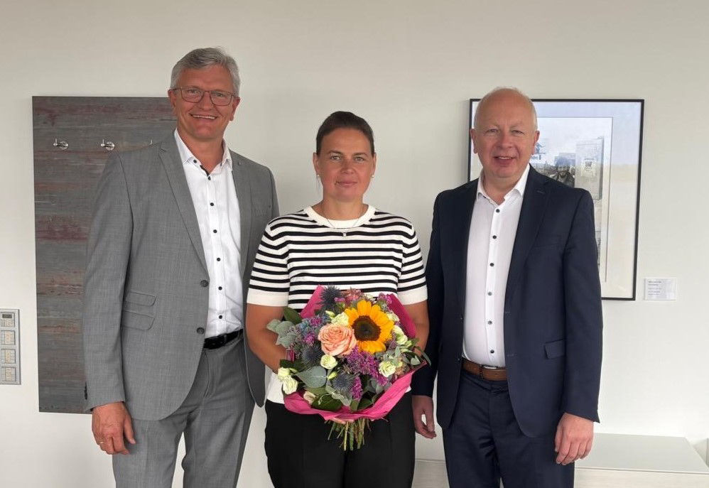 Zwei Männer und eine Frau in der Mitte mit Blumenstrauss