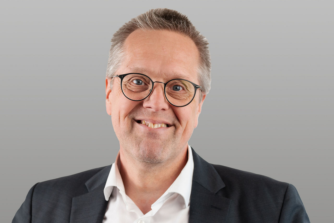 Firmenkundenberater Martin Müller vor grauem Hintergrund