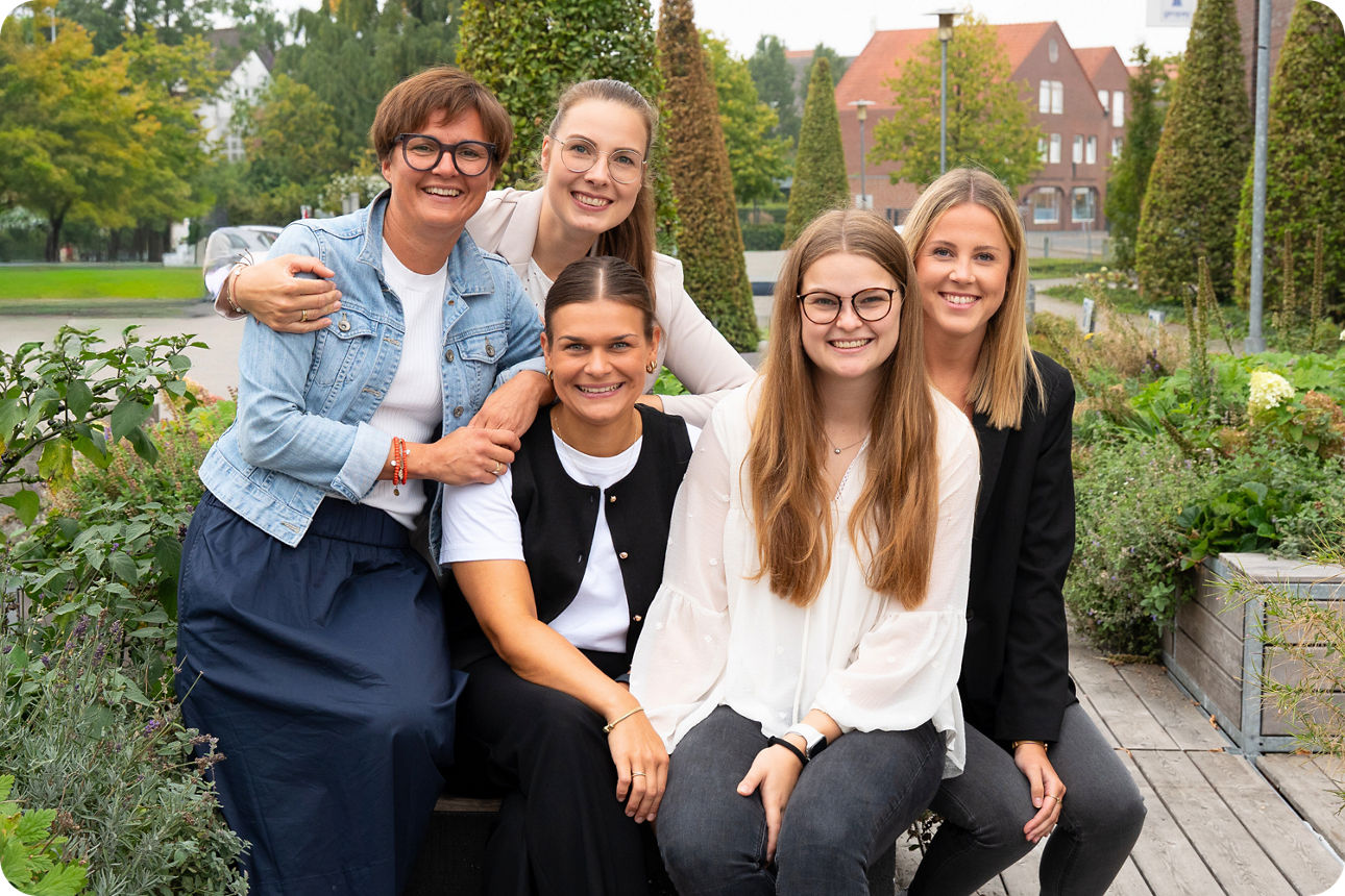 5 Frauen sitzen in einem Garten auf einer Bank