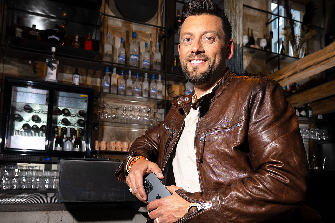 Mann mit Lederjacke lehnt an einer Bar