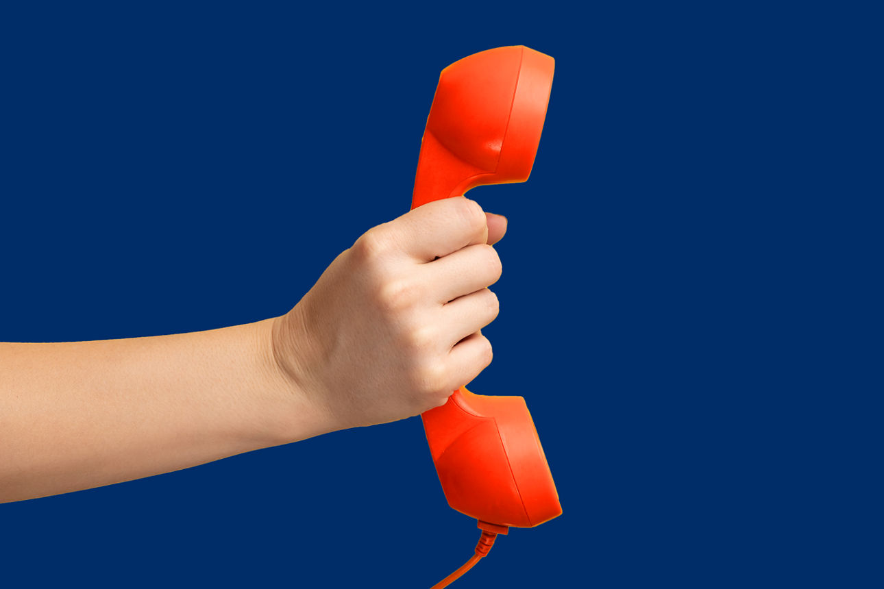 Eine hand hält einen orangenen Telefonhörer vor einem dunkelblauen Hintergrund