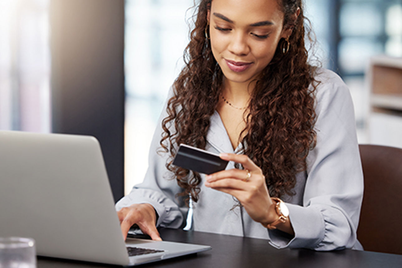 Dame am Schreibtisch mit Kreditkarte und Laptop