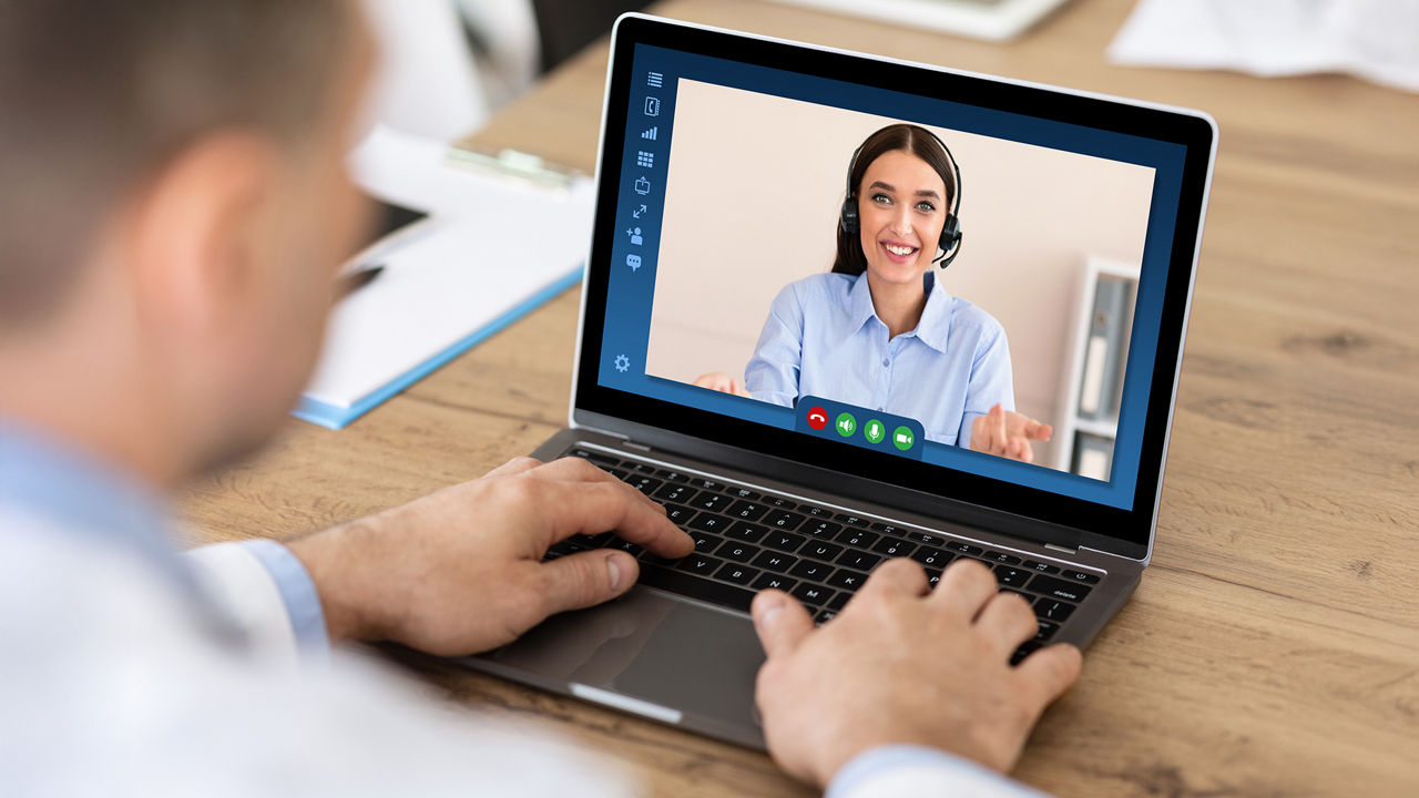 Mann sitz vor einem Laptop und führt ein Videogespräch mit einer Frau