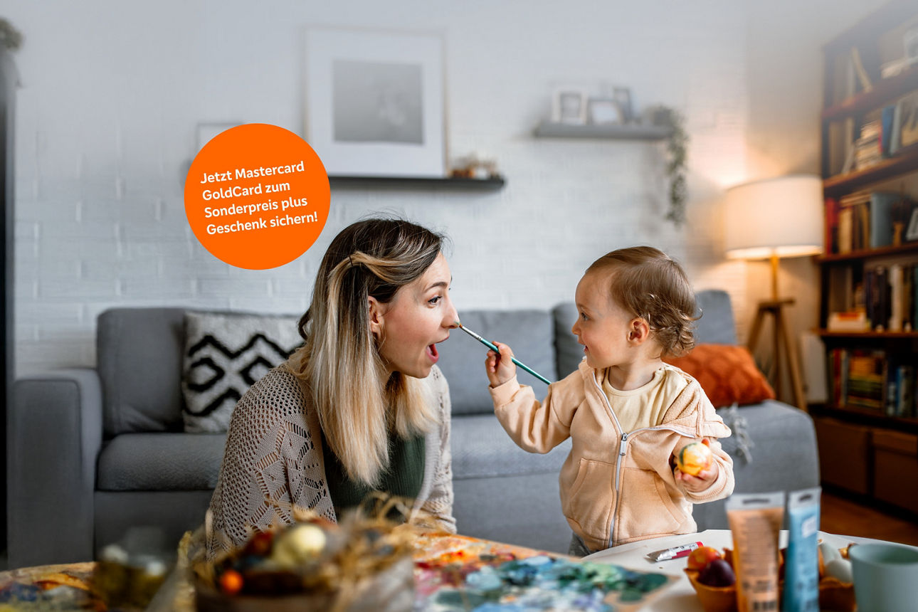 Kleinkind malt der Mutter beim Ostereieranmalen mit dem Pinsel auf die Nase.