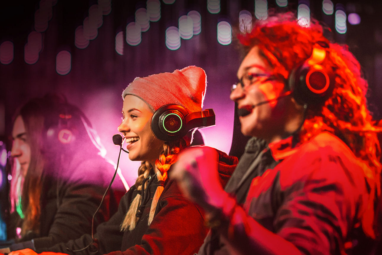 Drei junge Menschen sitzen mit Headset vor ihrem Computer und spielen ein Computerspiel.