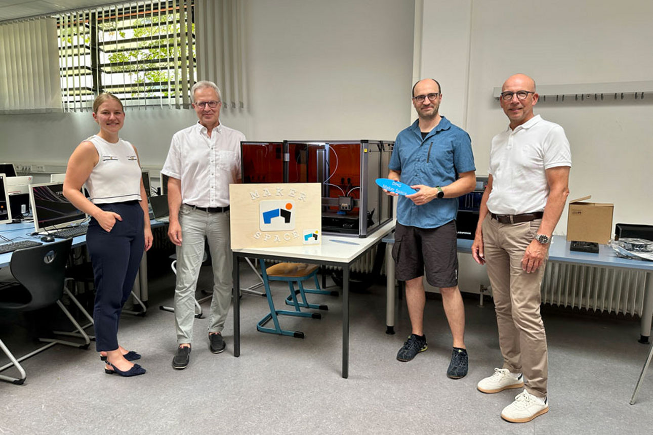 Vertreter der VR-Bank Würzburg und des Deutschhaus-Gymnasiums stehen im Maker-Space vor dem 3D-Drucker