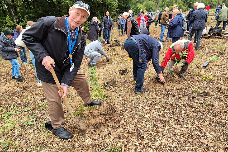 Ein Mitglied bei der Pflanzung eines neuen Baumes mit einem Spaten in der Hand