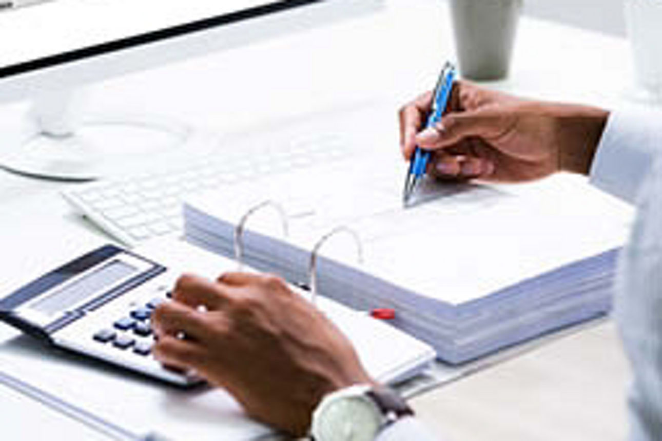 Ein Mann füllt am Schreibtisch ein Steuerformular am Computer aus