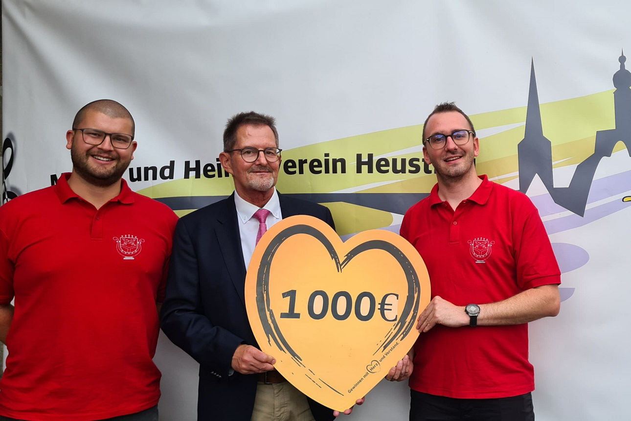 Hans-Peter Suckfüll (VR-Bank Main-Rhön) überreicht den Vorständen des Musik- und Heimatvereins Heustreu, Nico Benkert und Fabian Sauer, einen Scheck über 1.000 Euro