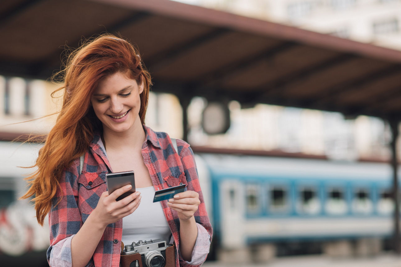 Frau kauft Dinge im Internet, während sie am Bahnhof auf den Zug wartet