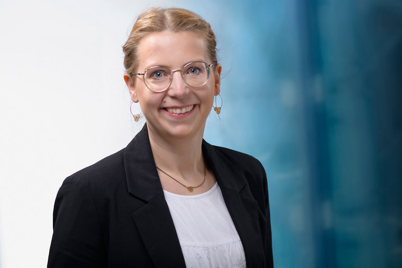 Mitarbeitende mit Brille schaut lächelnd in die Kamera