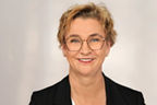 Ursula Maicherczyk hat kurze blonde lockige Haare, trägt eine leicht runde Brille und einen schwarzen Blazer