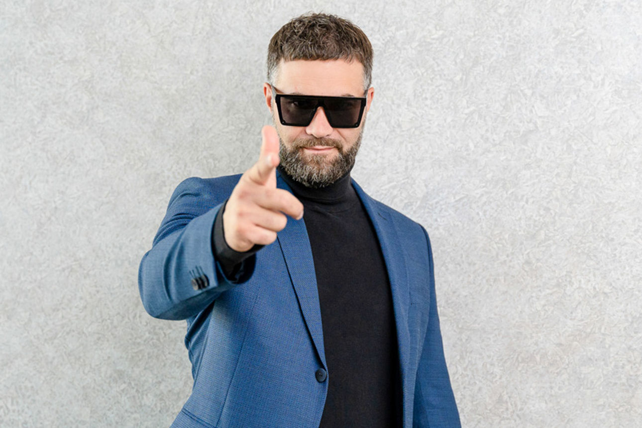 Mann mit Sonnenbrille zeigt mit Finger in die Kamera