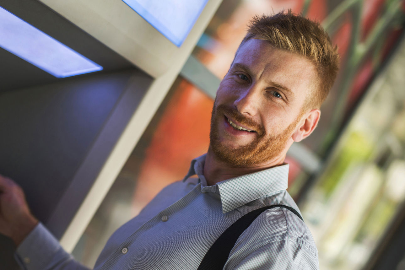 Ein Mann am Geldautomaten mit einer Karte in der Hand