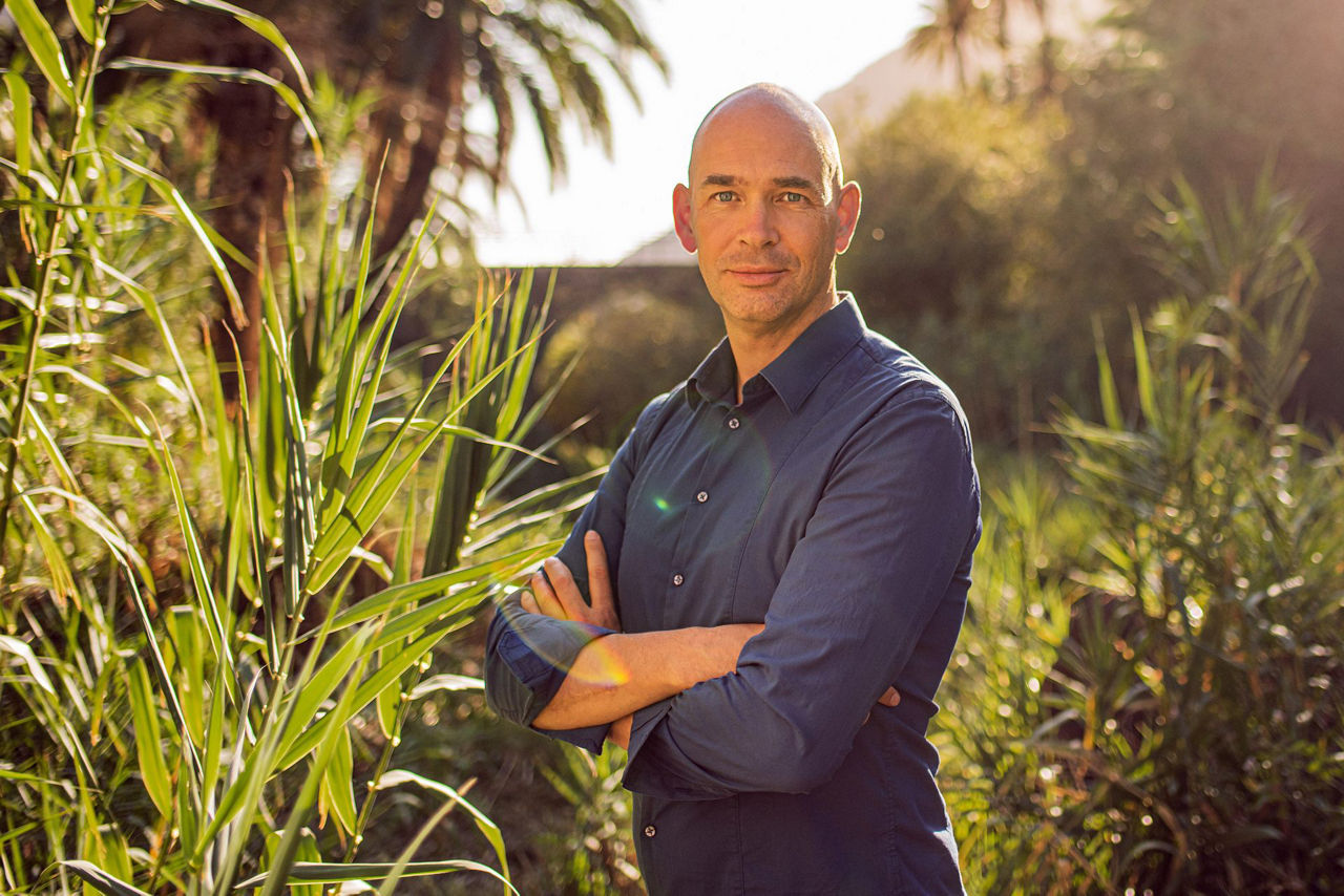 Portrait von Marc Wallert im Hintergrund und an den Seiten sind versch. grüne Pflanzen zu sehen. 