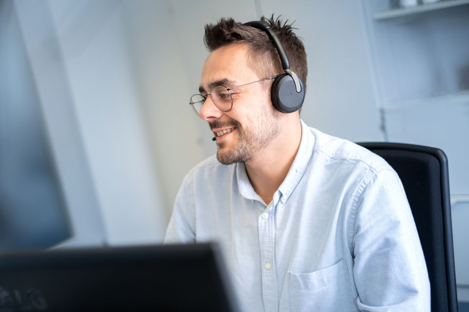 Bankmitarbeiter mit Headset schaut auf seinen Computer