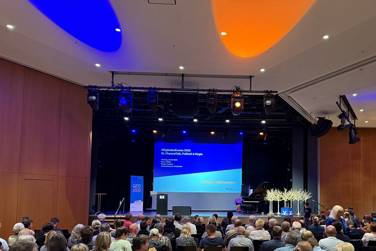 Bild einer Veranstaltung mit Blick Richtung Bühne, man sieht das Publikum in den Reihen sitzen