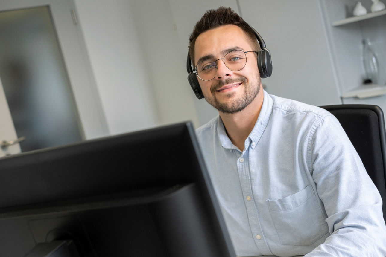 Bankmitarbeiter mit Headset schaut auf seinen Computer
