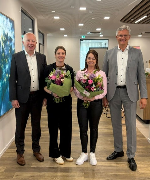 Zwei Frauen und zwei Männer haben sich zum Foto aufgestellt. Die Frauen in der Mitte haben einen Blumenstrauß in der Hand.