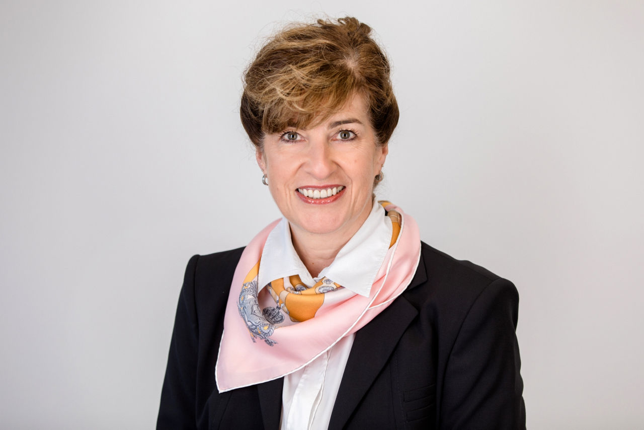 Eine lächelnder Frau schaut in die Kamera.