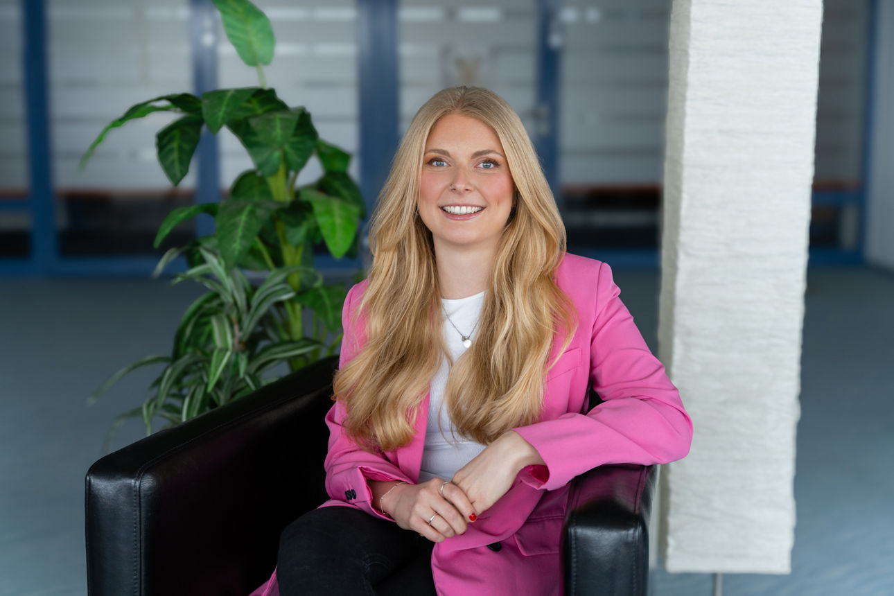Eine lächelnde Frau in hellen Büroräumen