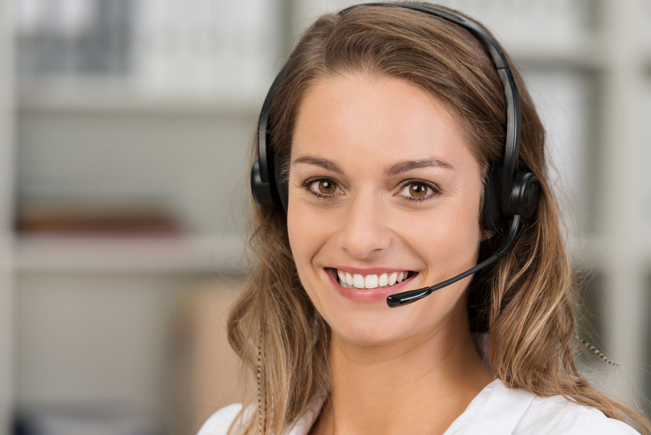 Young attractive woman with a friendly smile wearing a headset for online communication as professional virtual client support or customer service