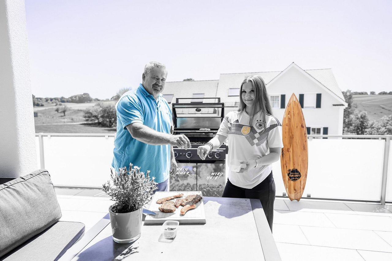 Eine junge Frau und ein Mann würzen ihr Grillfleisch.