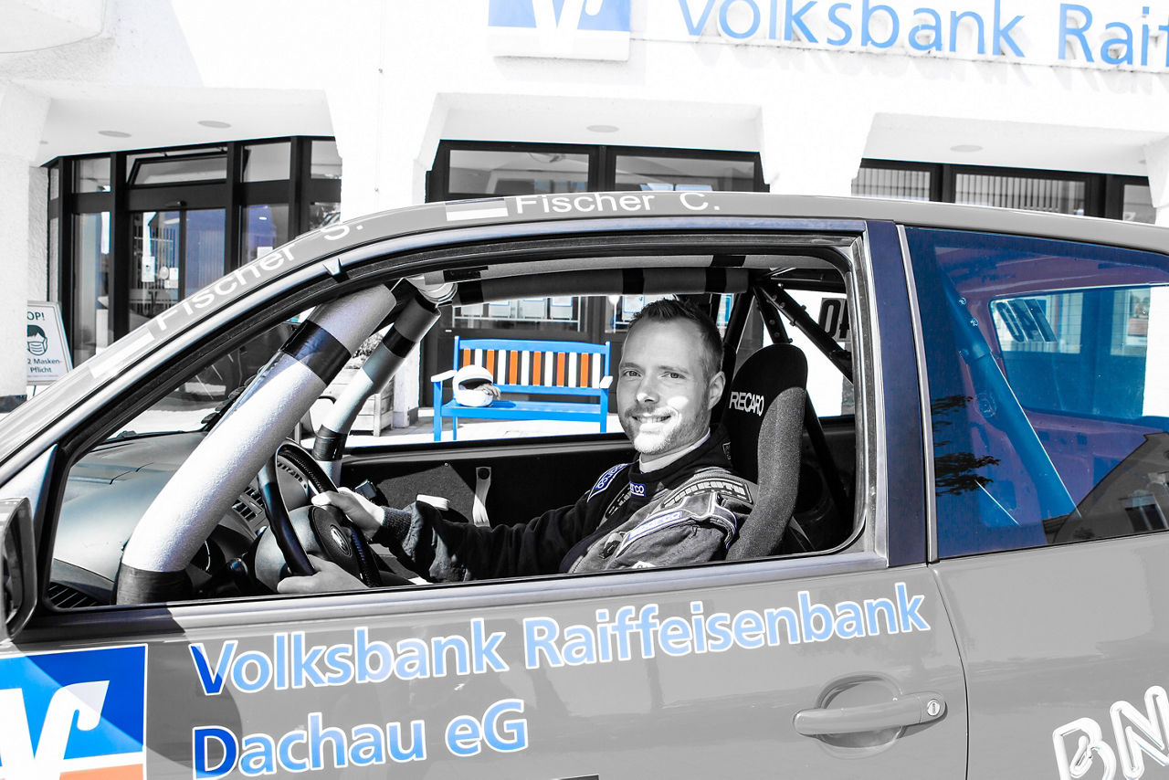 Mann sitz in einem Auto, dass sich vor einem Gebäude befindet