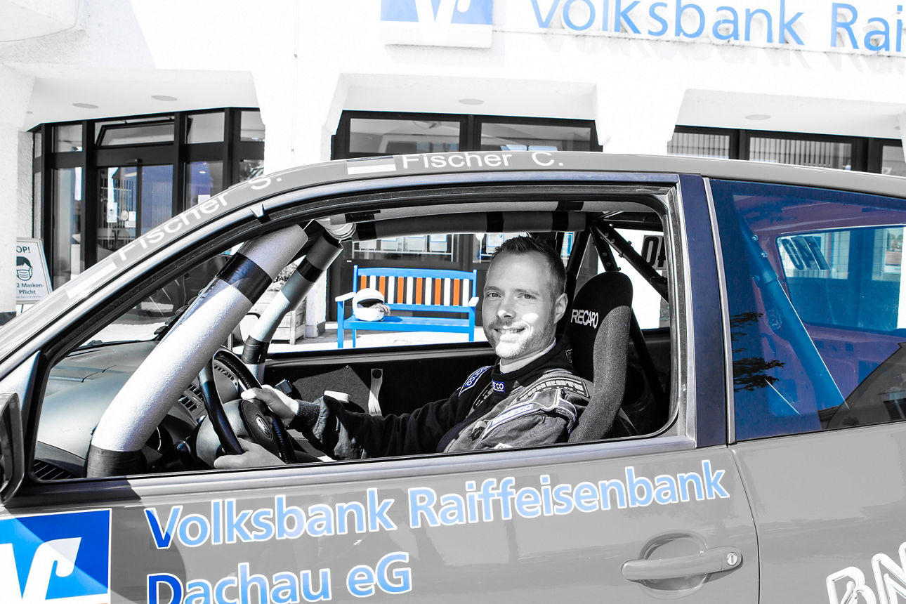 Mann sitz in einem Auto, dass sich vor einem Gebäude befindet