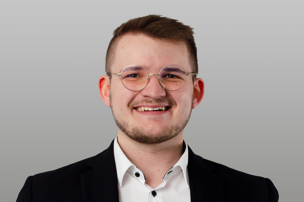 Privatkundenberater Florian Martens vor grauen Hintergrund