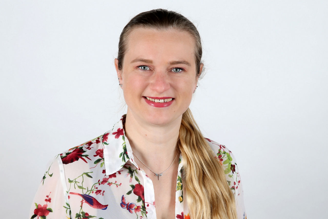 Eine lächelnder Frau schaut in die Kamera.