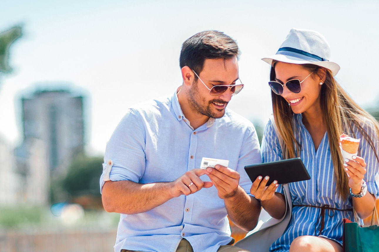 Ein Mann und eine Frau halten ein Smartphone und eine Kreditkarte in der Hand