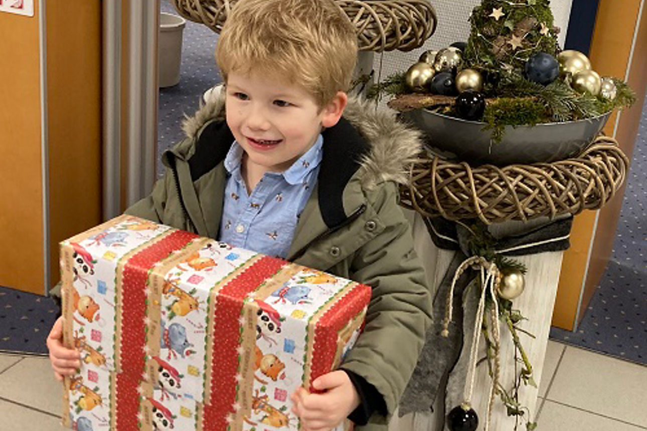 Ein Junge der sein Geschenk glücklich festhält.